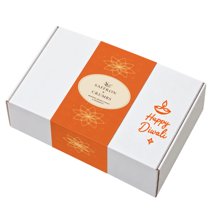 White Diwali gift box with a saffron-orange sleeve and the SC and whisk logo